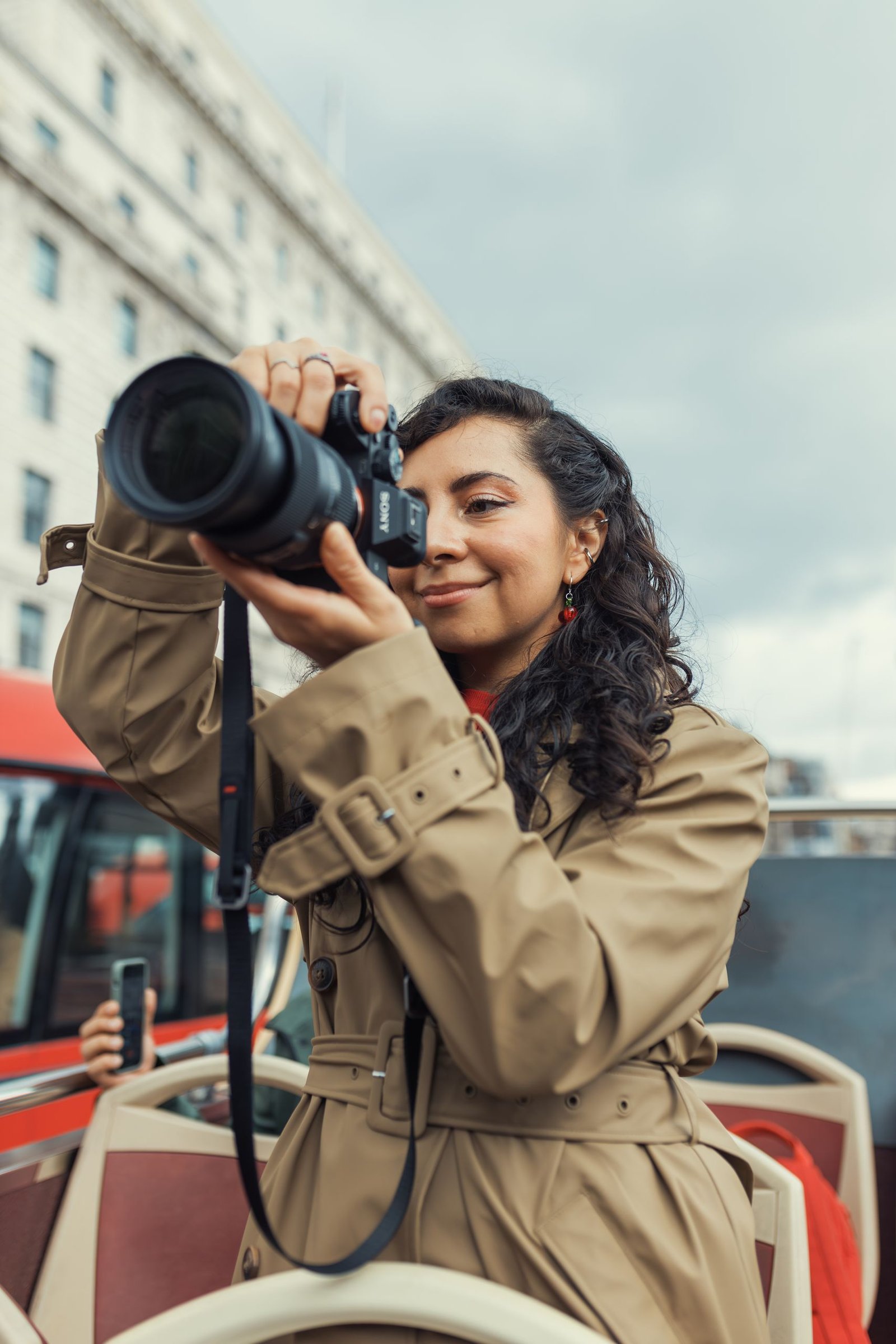 Female photographer capturing outdoor shots from a double-decker bus.
